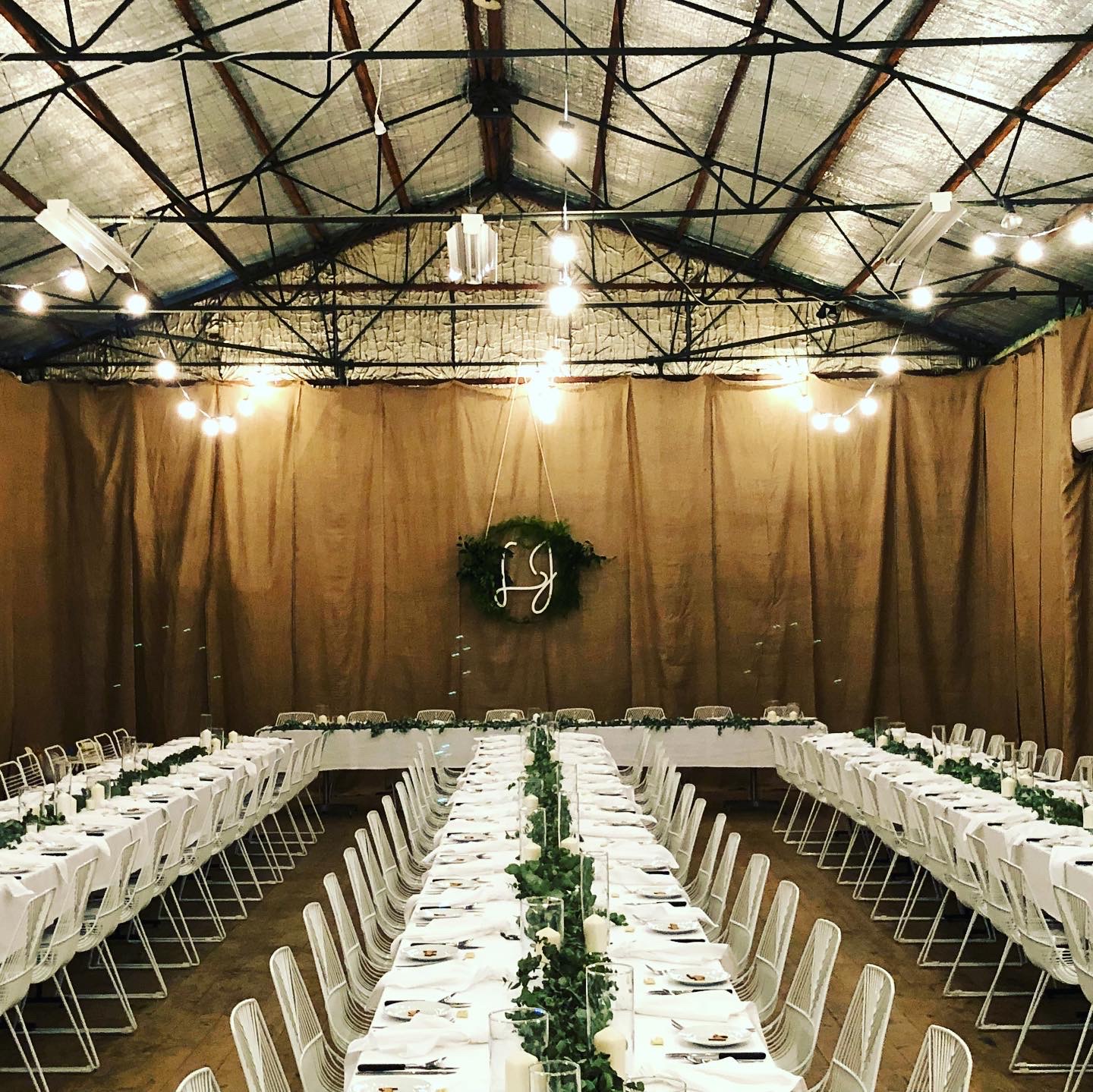 Long tables with greenery runners under draping