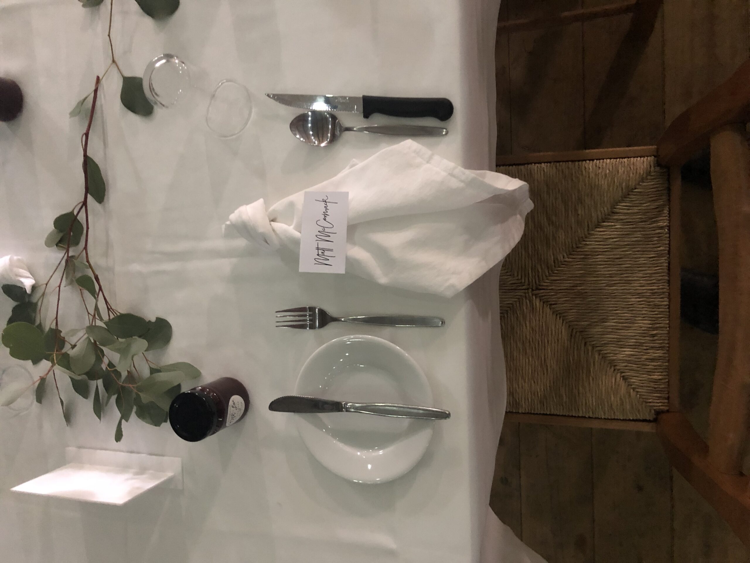Place setting with greenery on white linen